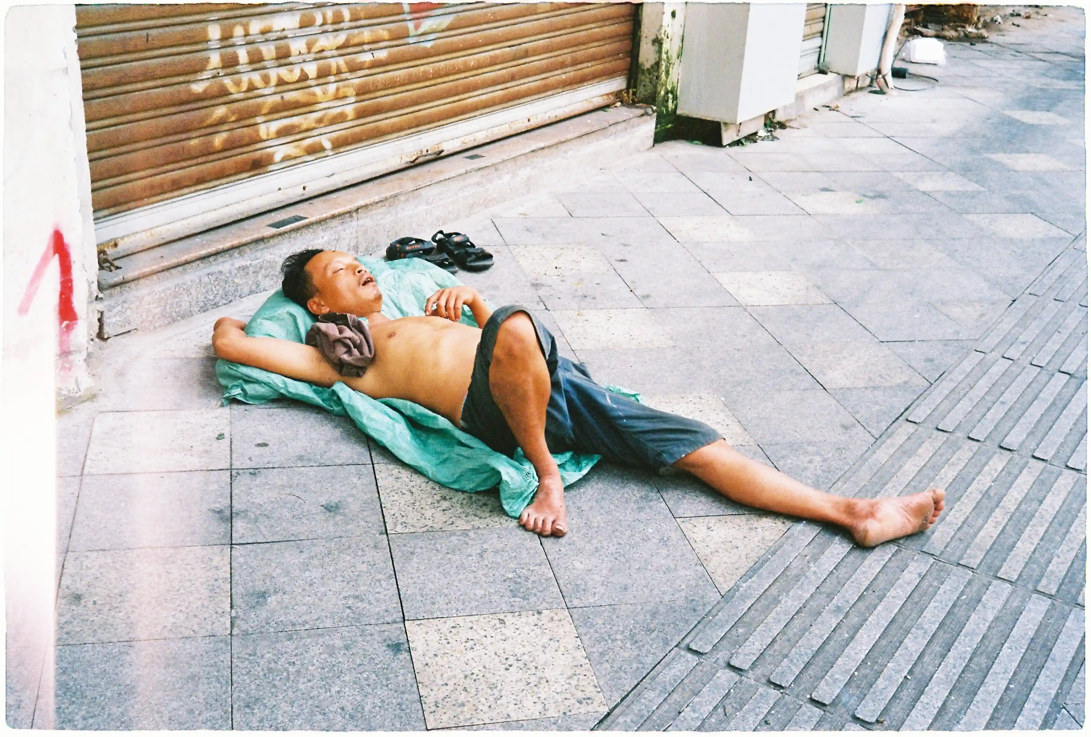 Ảnh chụp cận cảnh một người đàn ông đang ngủ trên vỉa hè bằng Rollei 35 SE, minh họa sự hoạt động êm ái của màn trập lá. Rollei 35 SE, f/11, 1/125s, Fuji 400