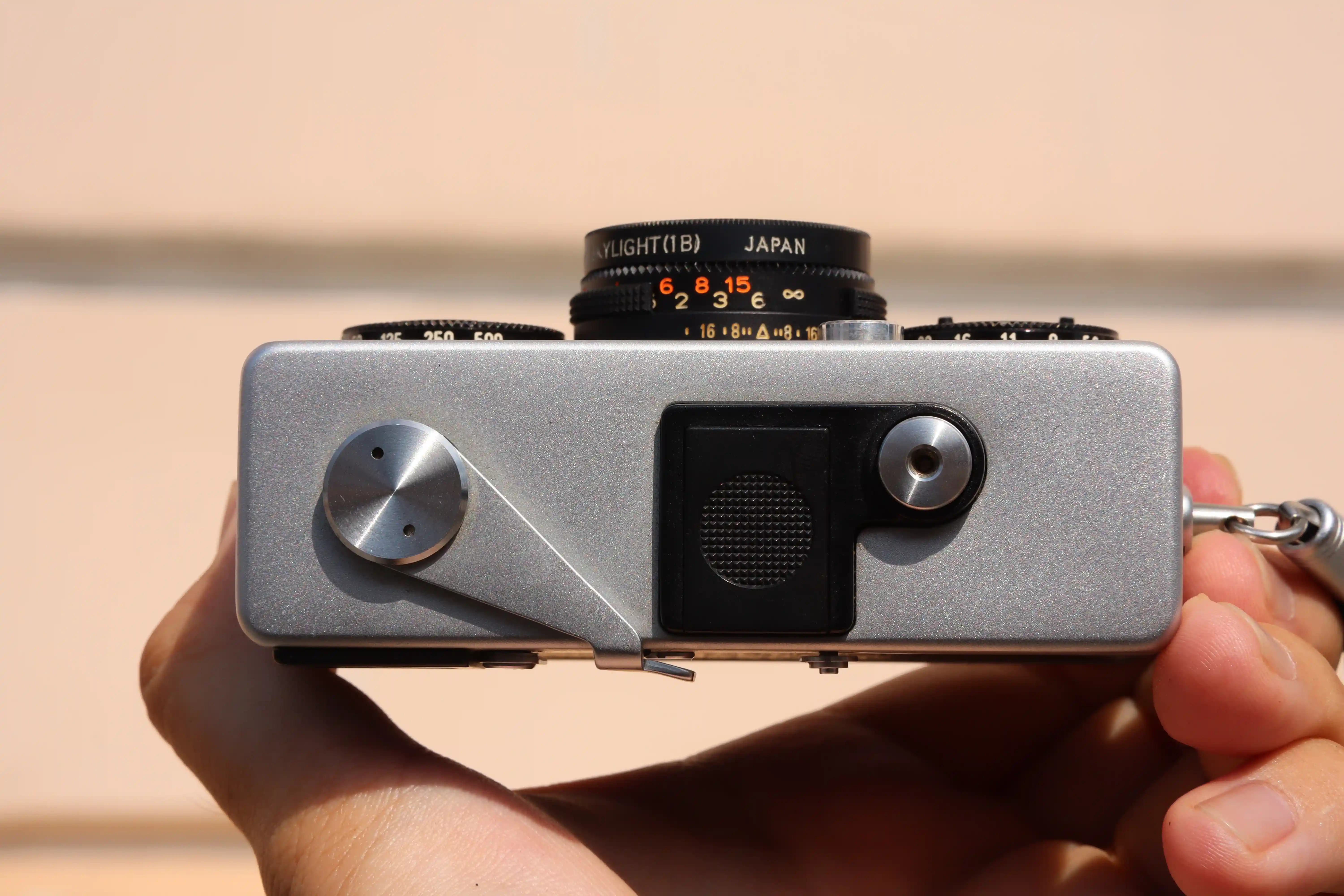 Mặt trên của máy Rollei 35 SE gồm có nút chụp, cần lên phim và khay pin.