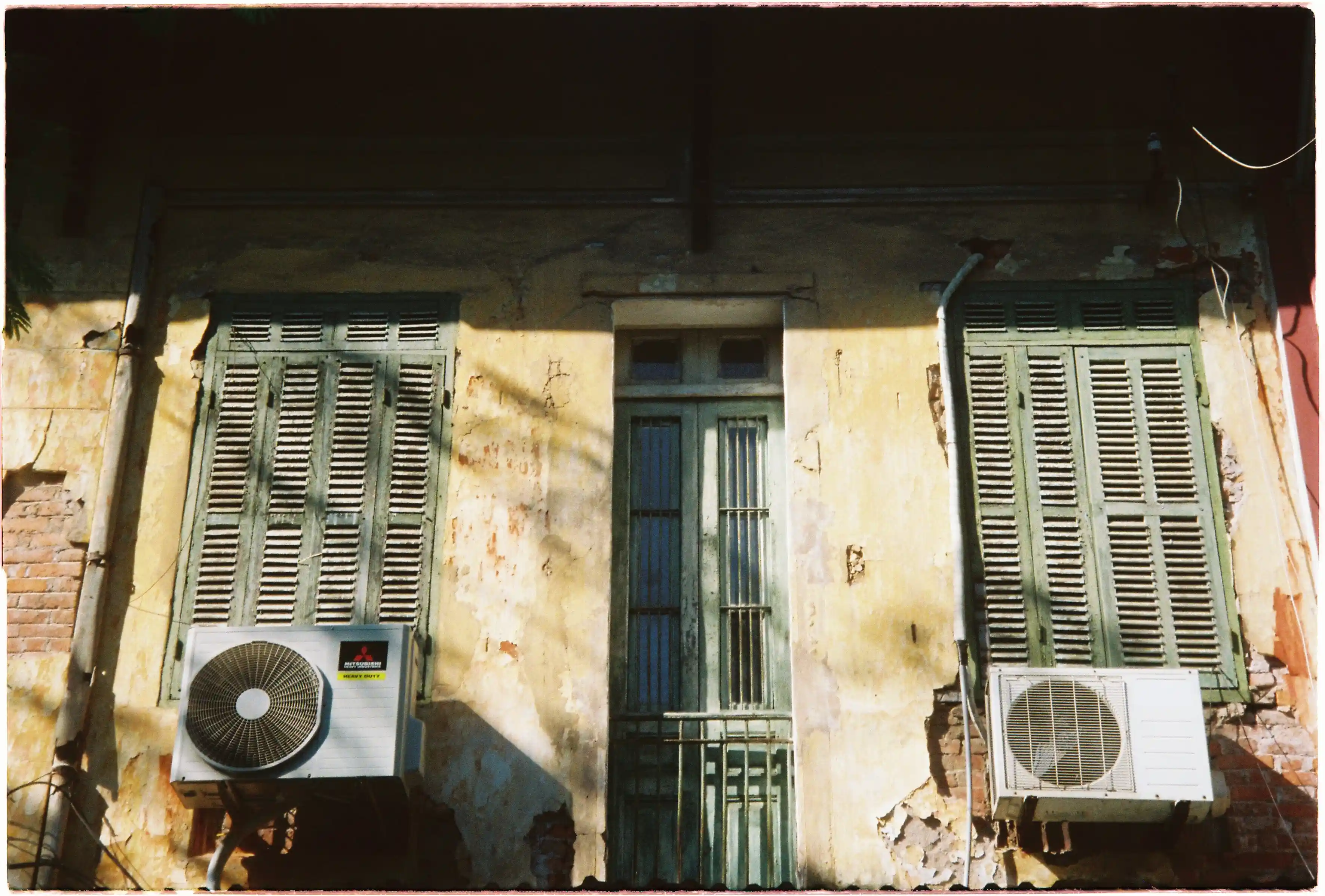 Mặt tiền ngôi nhà cổ màu vàng tróc sơn với cửa sổ lá sách xanh: Ảnh chụp chi tiết kiến trúc tại tiêu cự 60mm bằng Canon Autoboy Tele 6