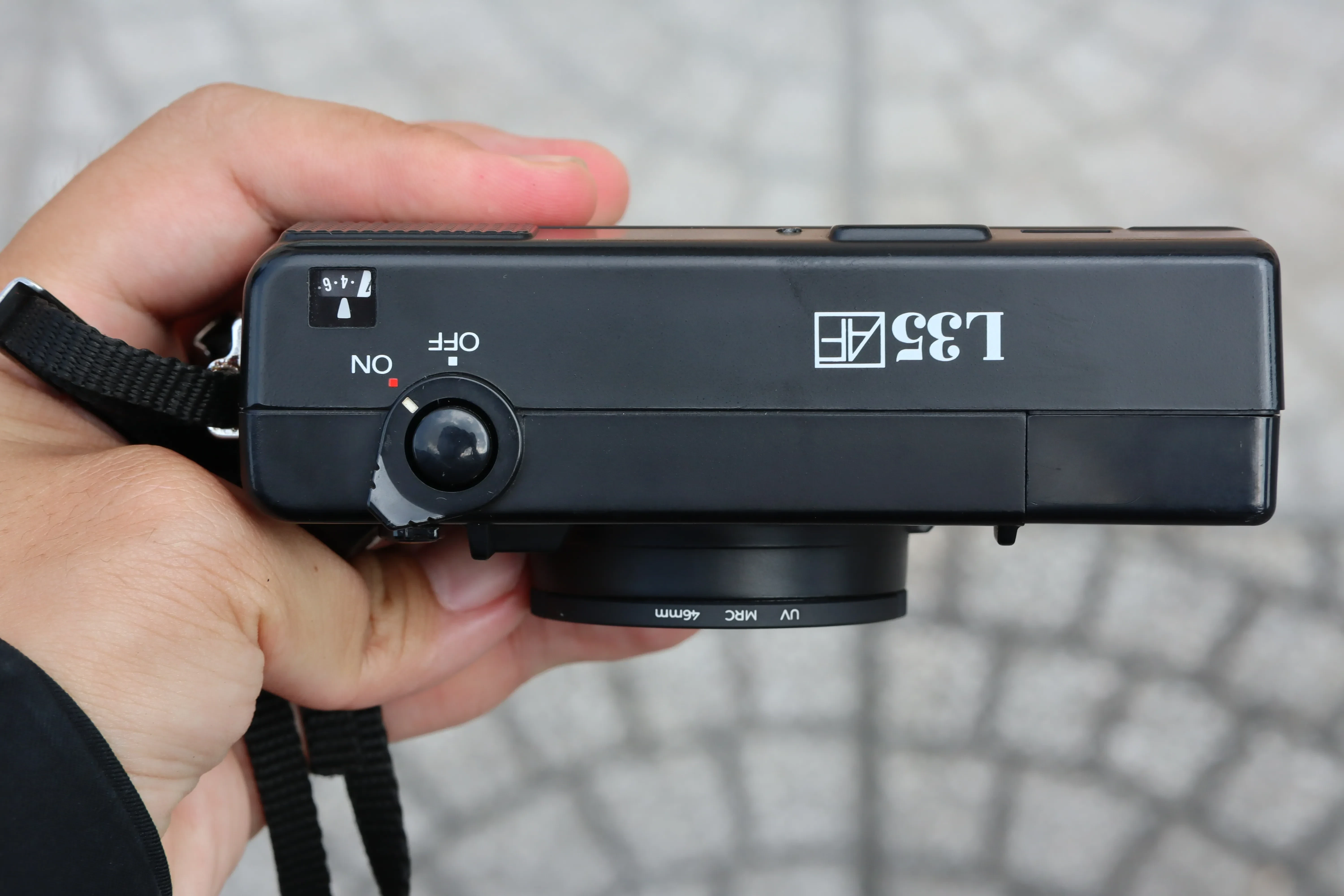 Cận cảnh mặt trên máy ảnh Nikon L35AF, cho thấy vòng xoay chức năng ON/OFF và thương hiệu máy cùng với cửa sổ đếm số kiểu đã chụp.