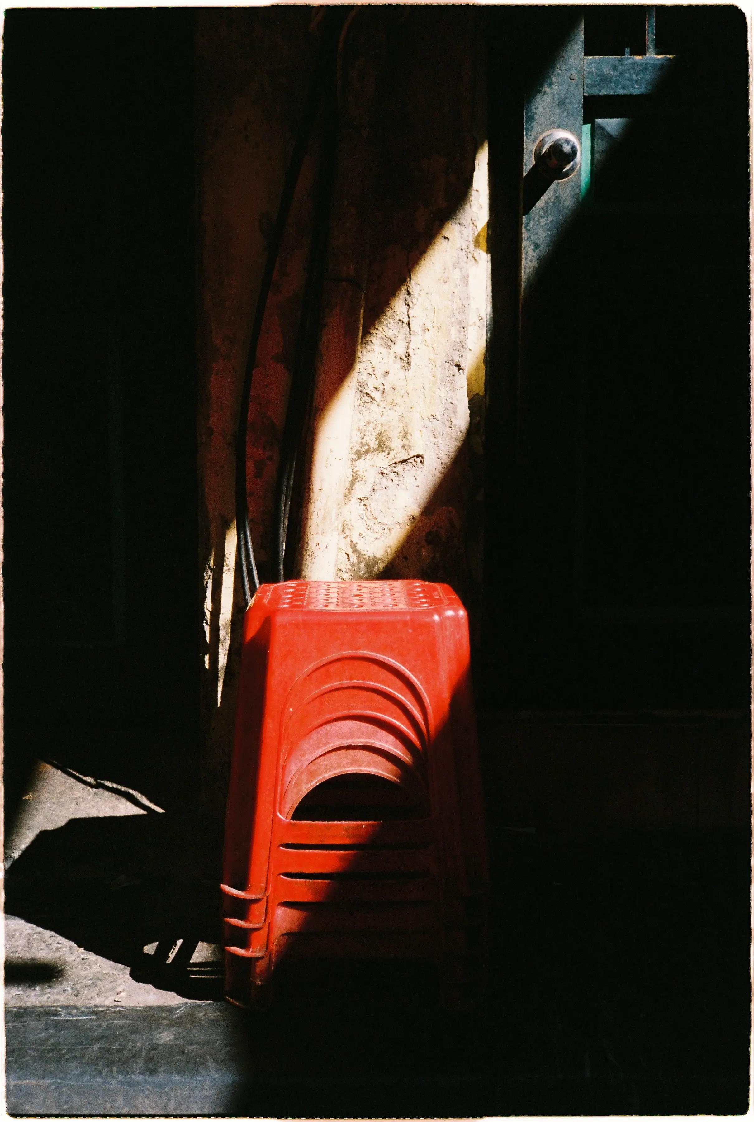 Ảnh chụp tĩnh vật chồng ghế đỏ dưới vệt nắng gắt bằng Nikon L35AD3, thể hiện độ tương phản cao giữa vùng sáng và bóng tối - Fuji 400