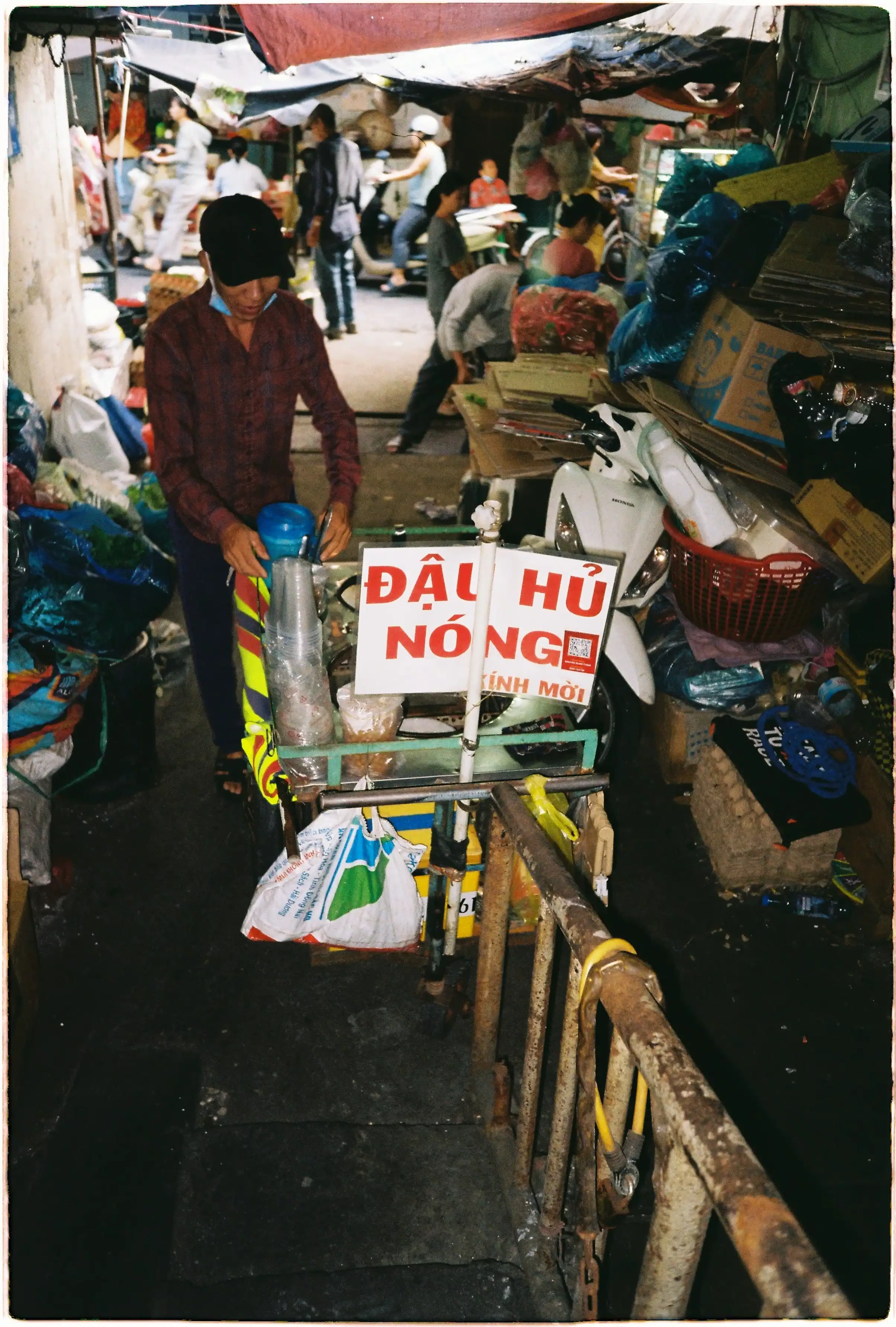 Ảnh chụp người đàn ông kéo xe hàng ở chân cầu thang chung cư tối, sử dụng flash của Fuji Tiara để cân bằng với ánh sáng ban ngày bên ngoài - Kodak Gold 200