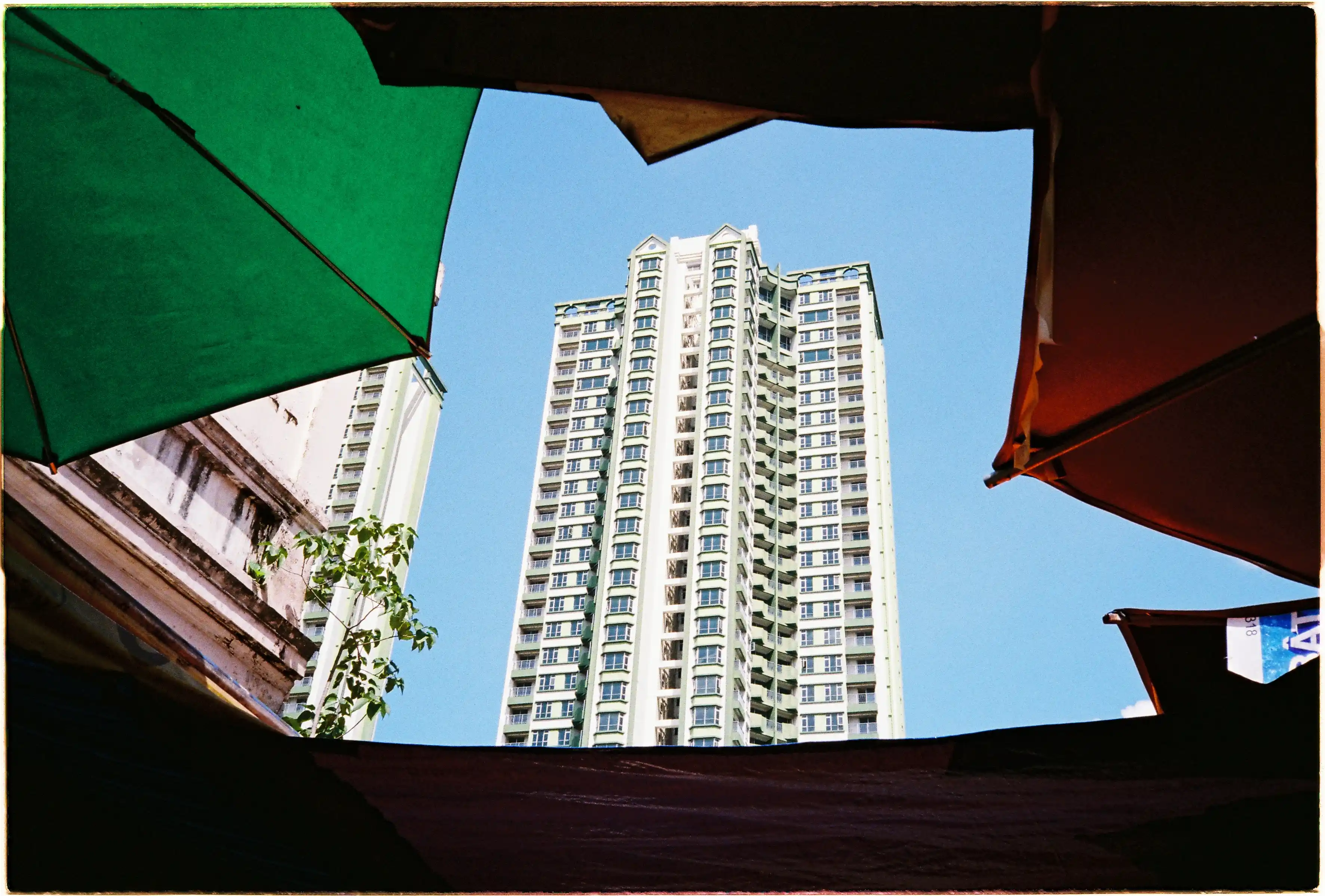 Ảnh chụp tòa nhà Thuận Kiều Plaza với máy Nikon L35AF, được khung bởi mái che chợ, thể hiện màu sắc rực rỡ - Fuji 400.