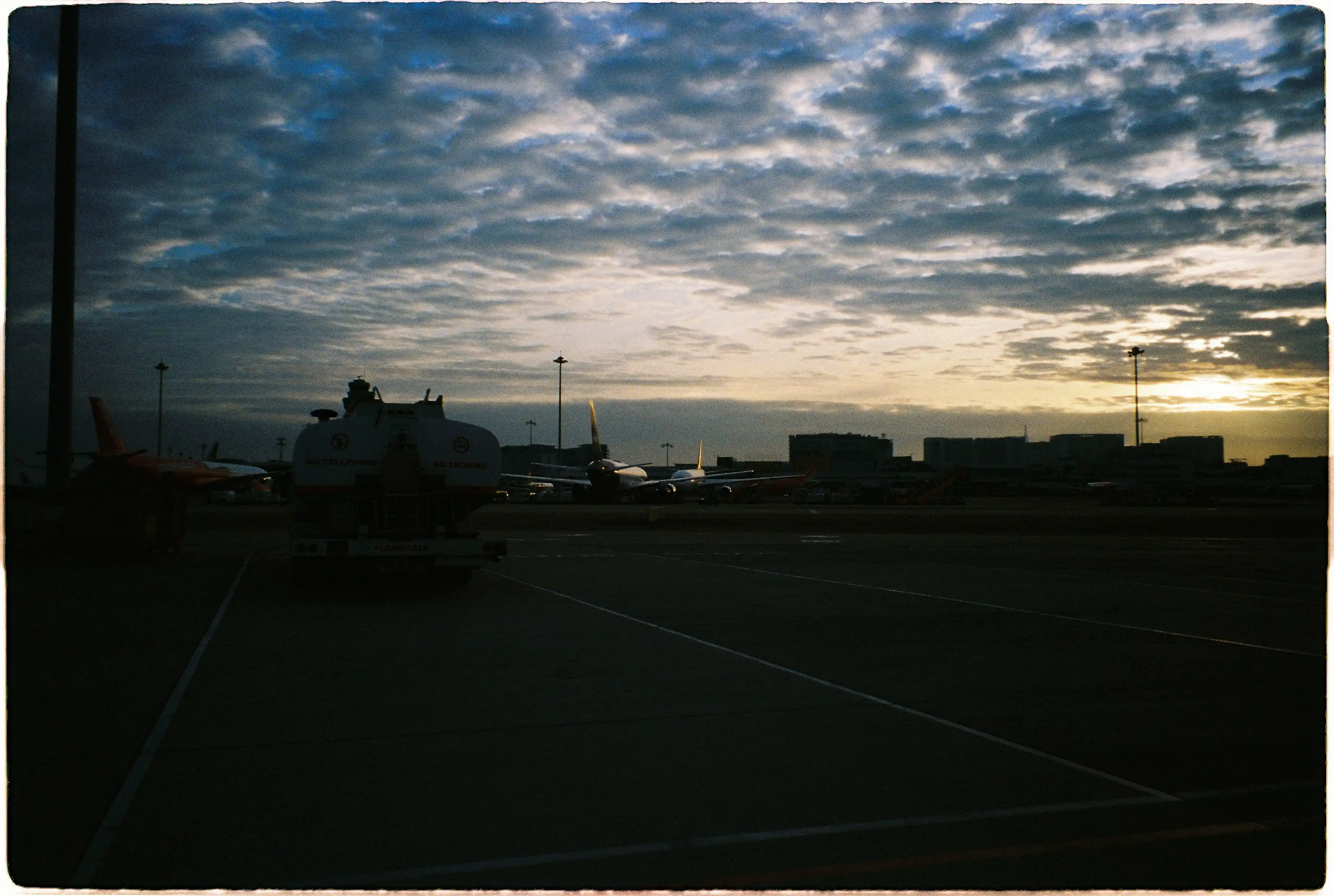 "Bầu trời nhiều mây với các sắc độ xanh và vàng ấn tượng, ảnh chụp tại sân bay bằng chế độ Auto của Pentax Espio 120 SW II - Fuji 400